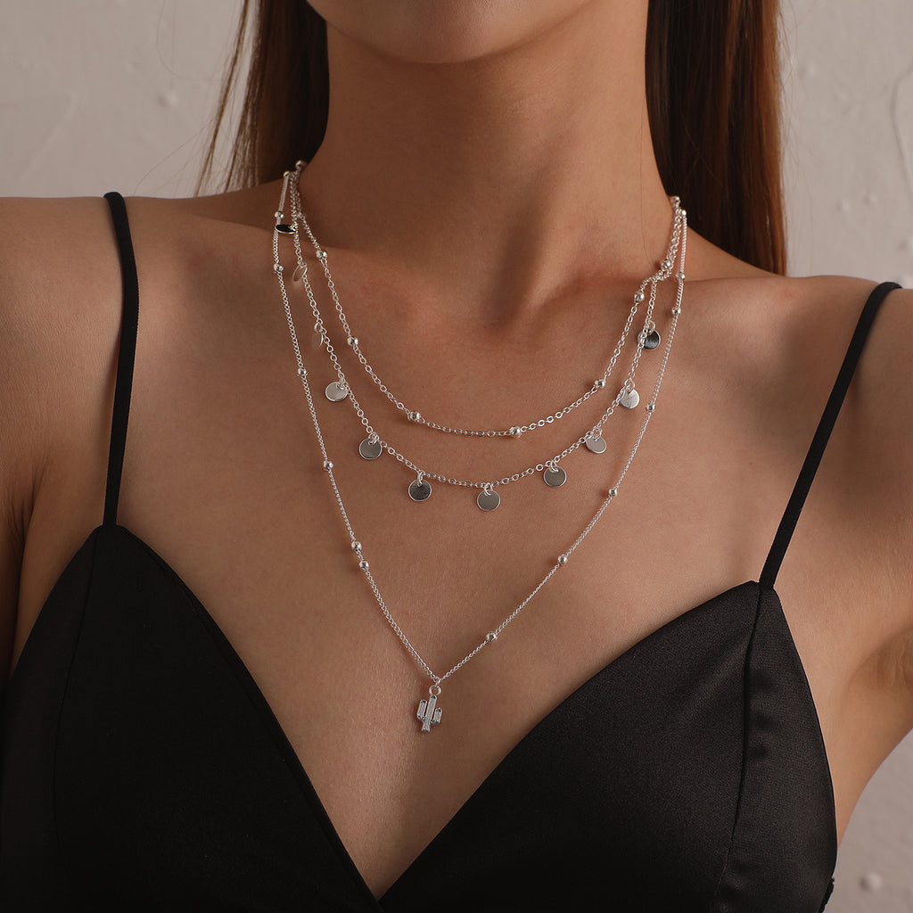 A multi-layered necklace featuring a round cactus pendant and a women's round bead chain