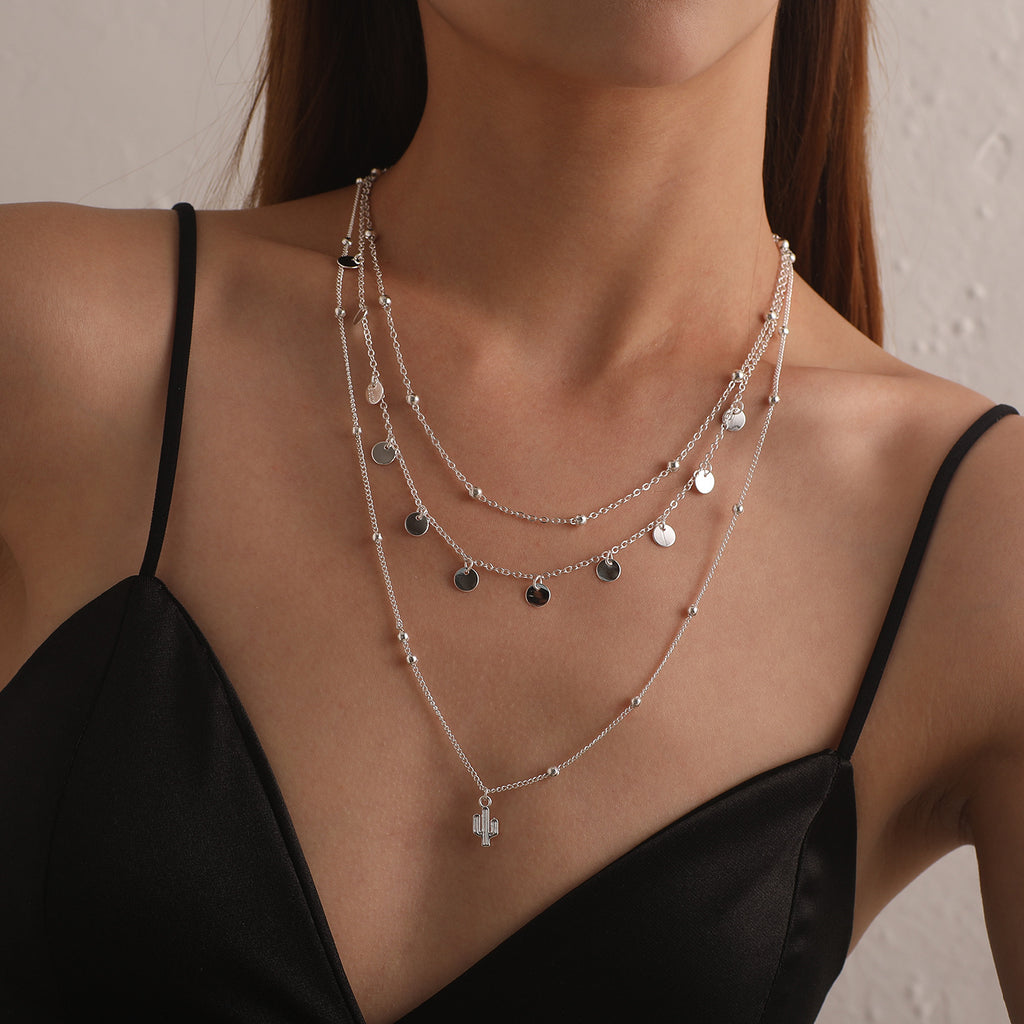 A multi-layered necklace featuring a round cactus pendant and a women's round bead chain