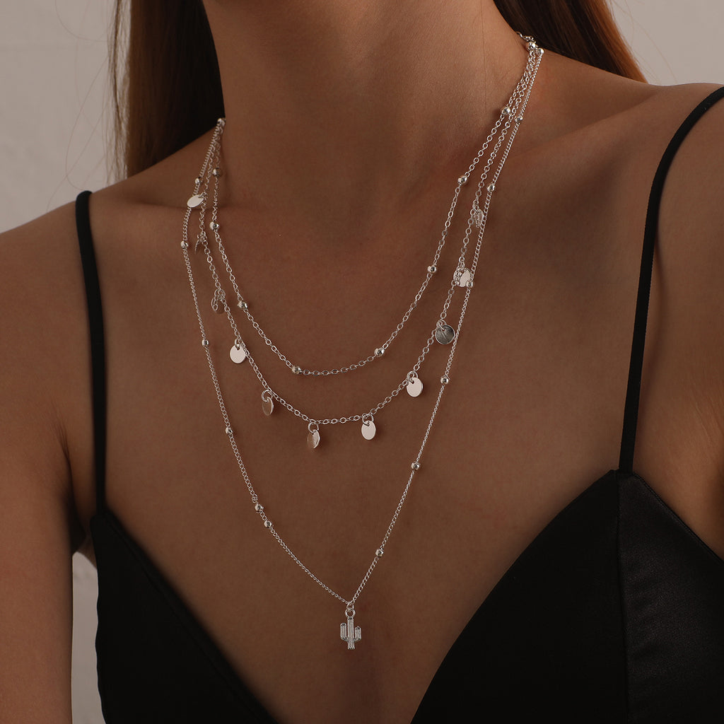 A multi-layered necklace featuring a round cactus pendant and a women's round bead chain